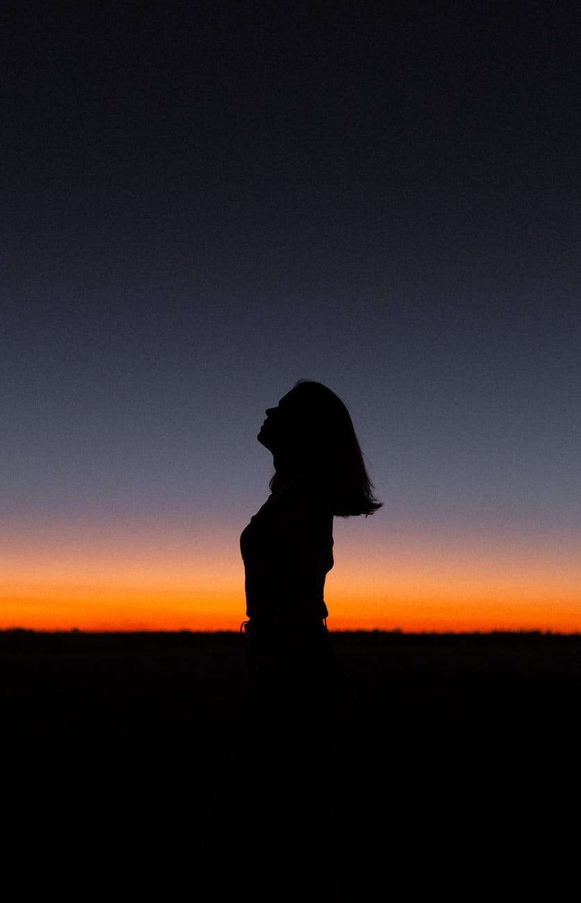 silhouette of female against colorful sky at sunset